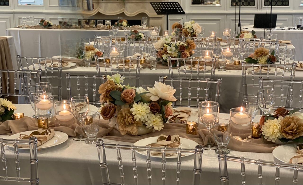 Reception table with neutral palette, low centerpieces, and warm candlelight