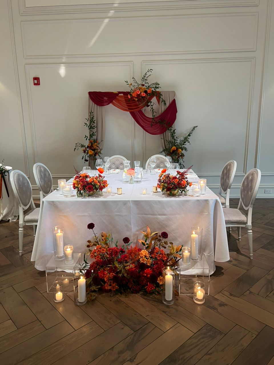 Autumn wedding with burgundy and orange florals, dramatic fabric draping